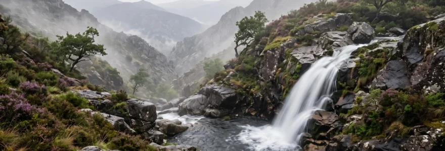 Cascade sauvage dévalant des rochers de granit dans un paysage de montagne brumeux du nord du Portugal