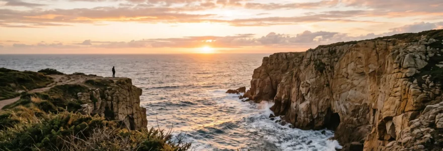 Silhouette d'un promeneur face à un coucher de soleil embrasant les falaises de la côte portugaise